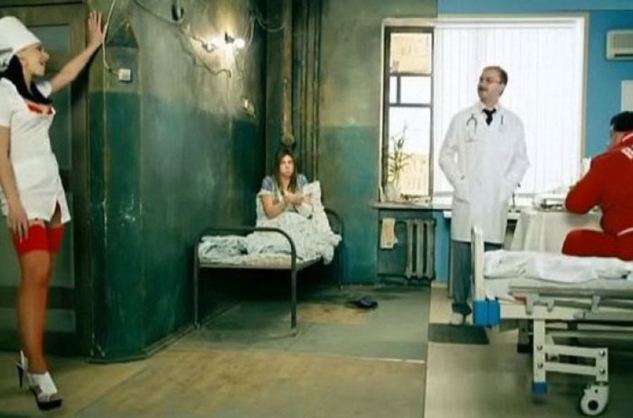 Медсестра сосет двум пациентам через специальные дырки в стене
